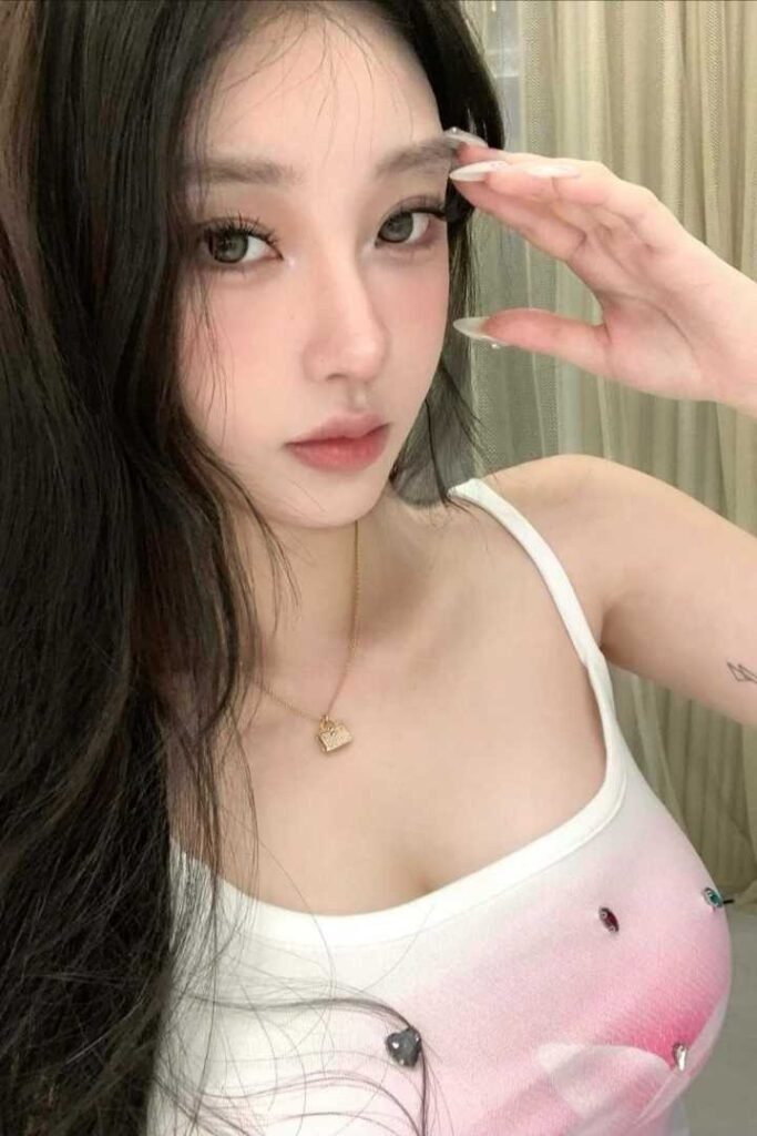 Portrait of a young woman with long dark hair, wearing a white tank top.