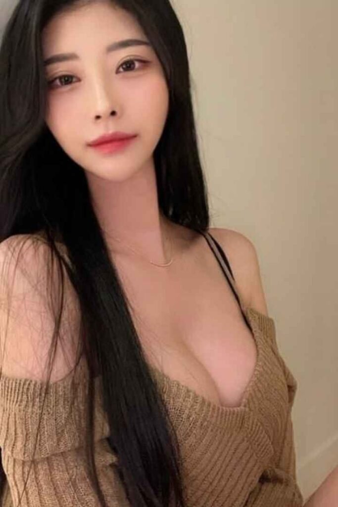 Attractive young woman with long black hair, wearing a brown sweater.